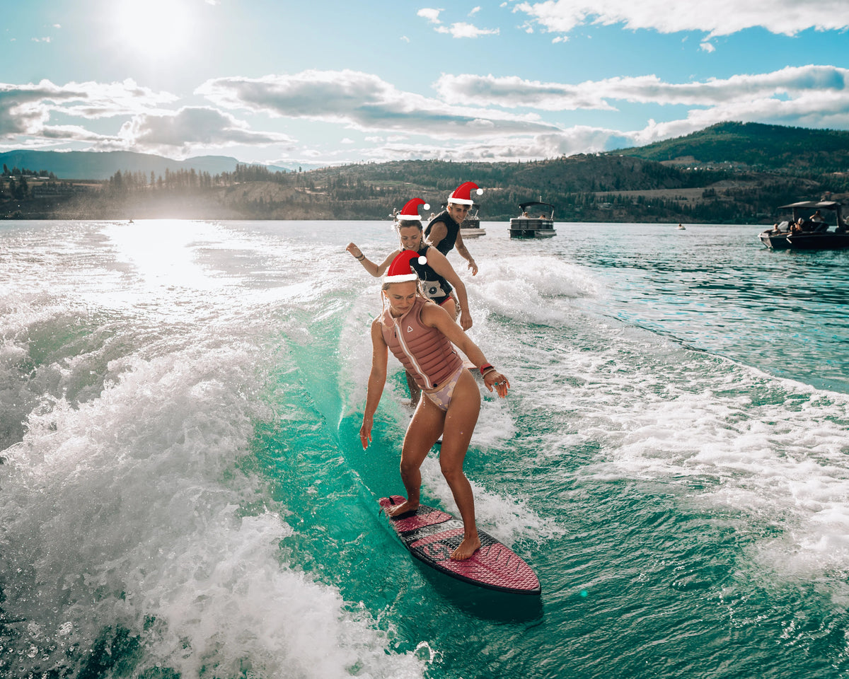 Three Kanuk team riders wakesurfing together in Santa hats